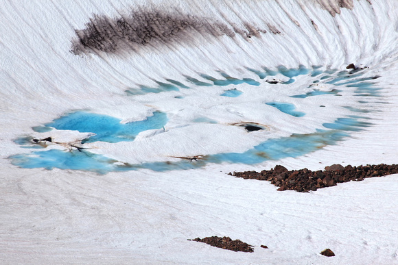 A glacial tarn emerges from ice and snow